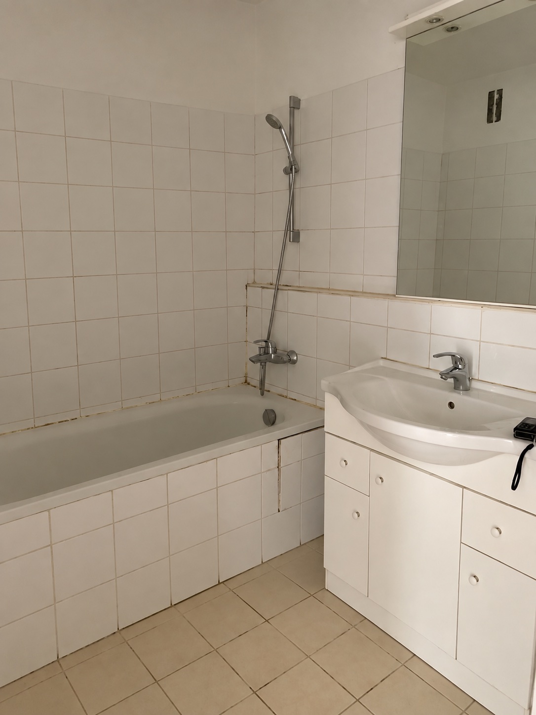 Avant rénovation : baignoire, carrelage clair et meuble vasque blanc